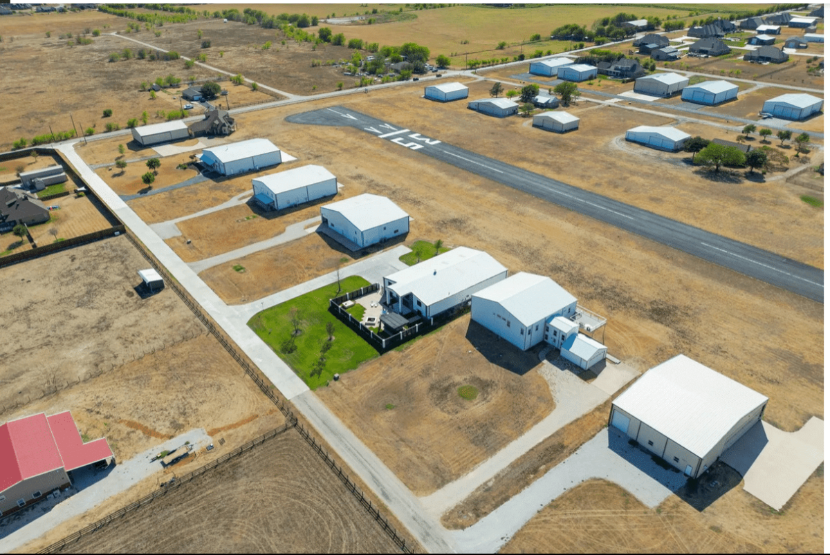 Aerial view of a huge house with a hangar and runway