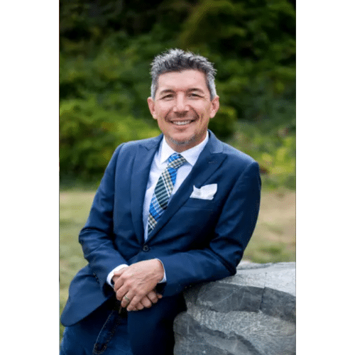 A real estate agent wearing a dark blue blazer and a statement tie